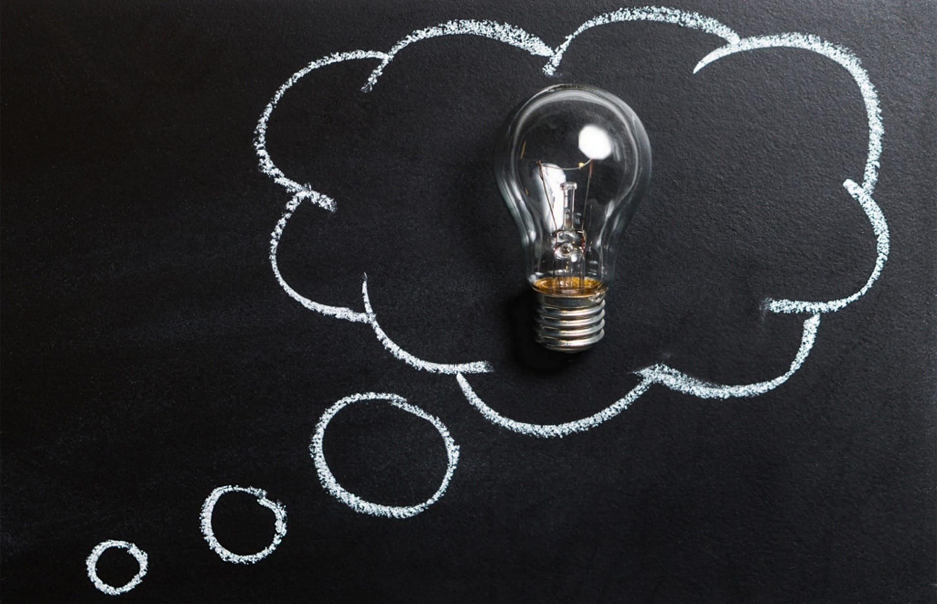 Light bulb in a chalk-drawn thought bubble on a blackboard