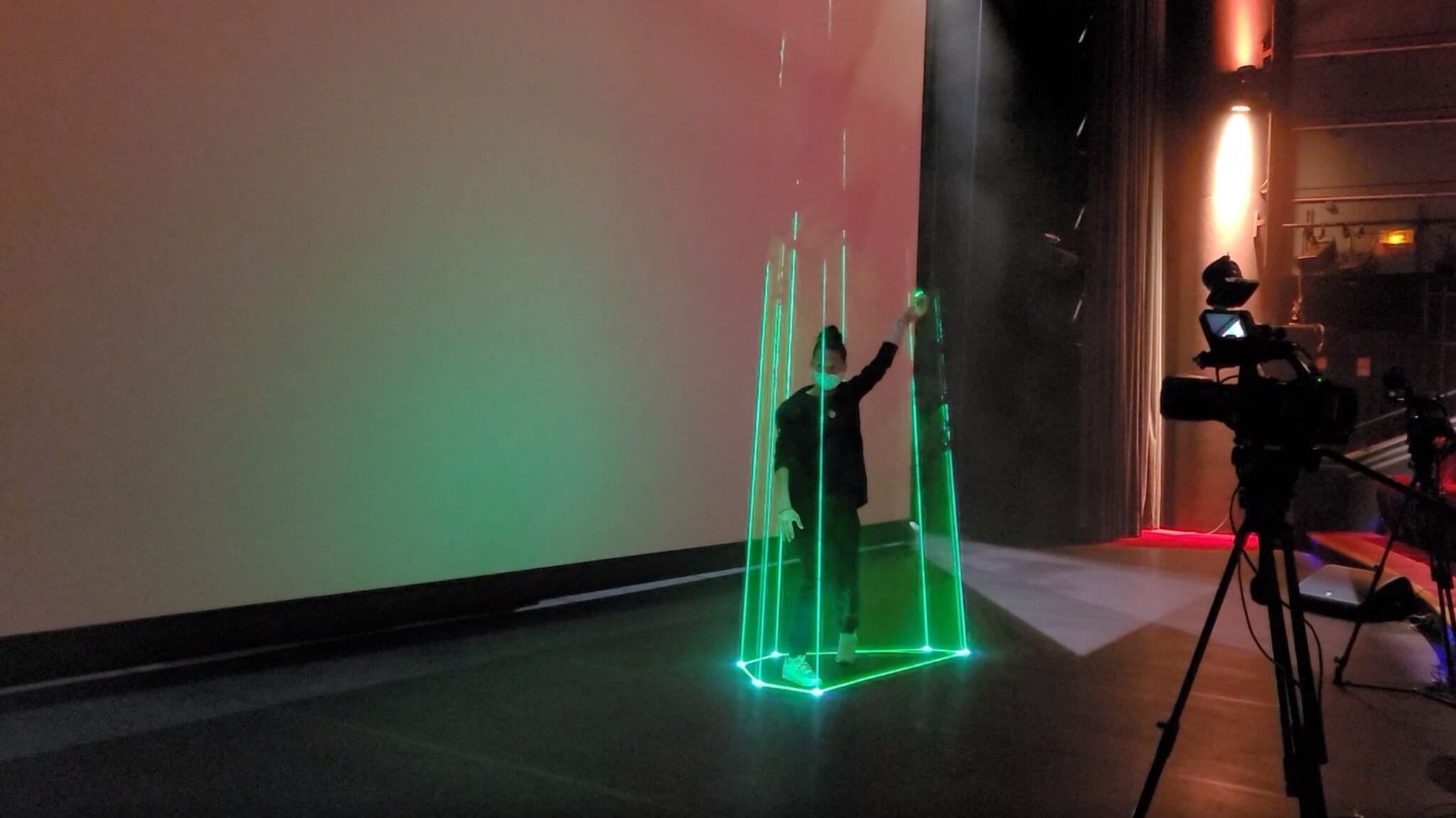 Flame backstage: dancer in a cone of light filmed by a camera