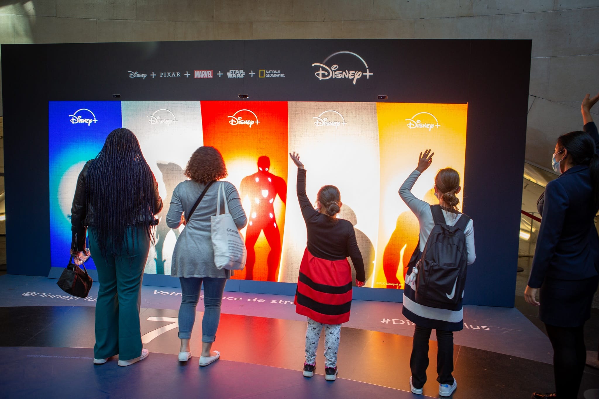 Visitors in front of the interactive Disney+ shadow wall in a station