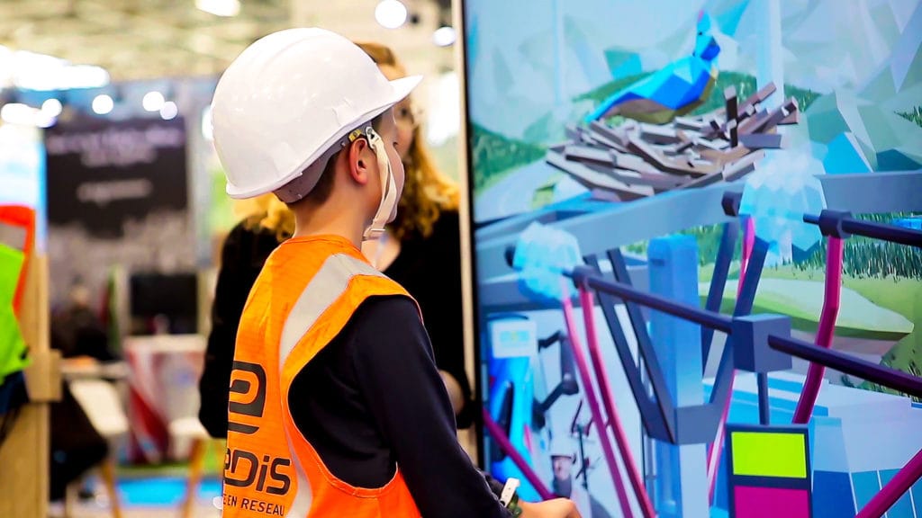 Child in a hard hat and Enedis vest playing the immersive quiz on a screen