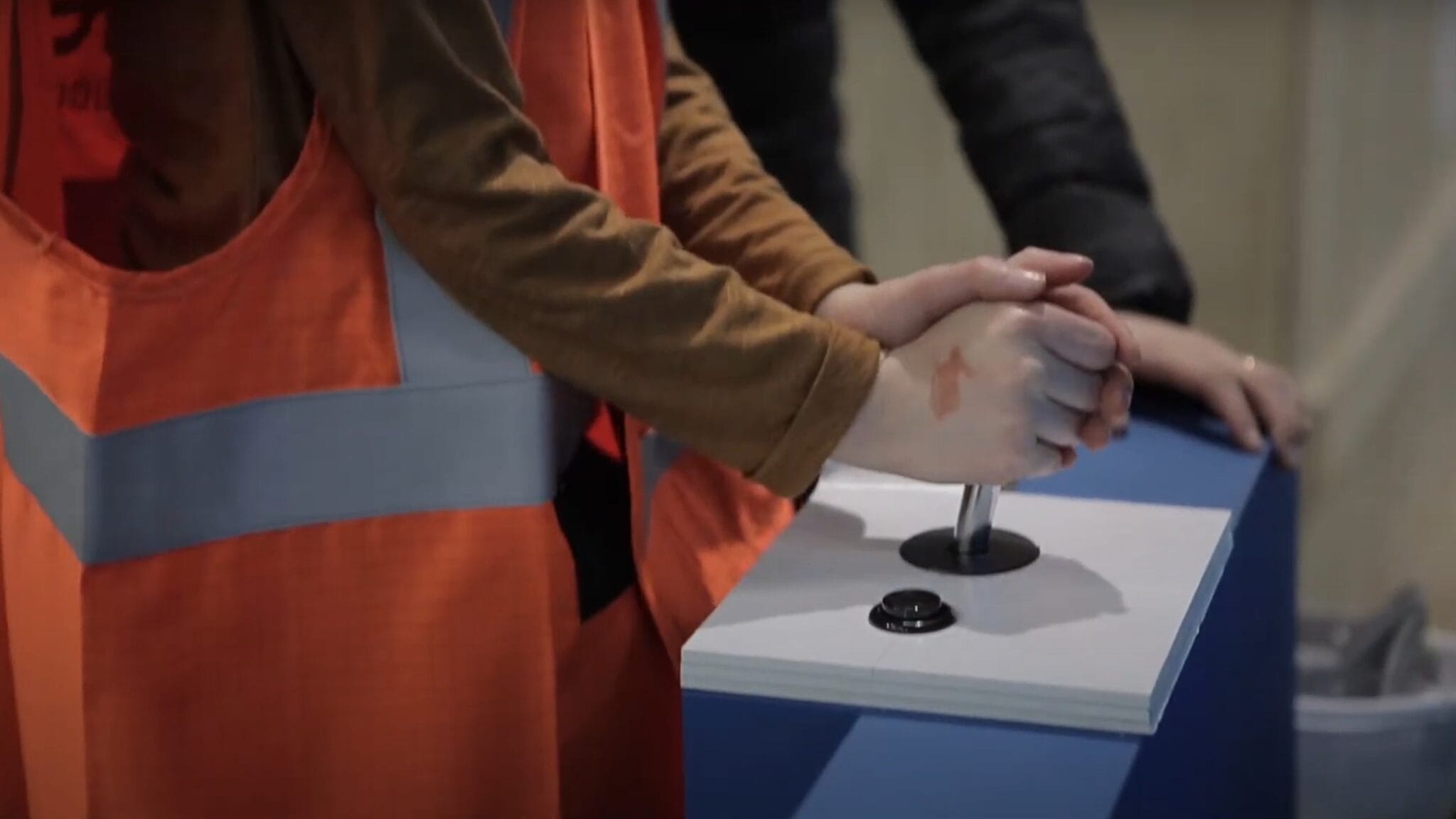 Children's hands in orange vests using the interactive quiz joystick