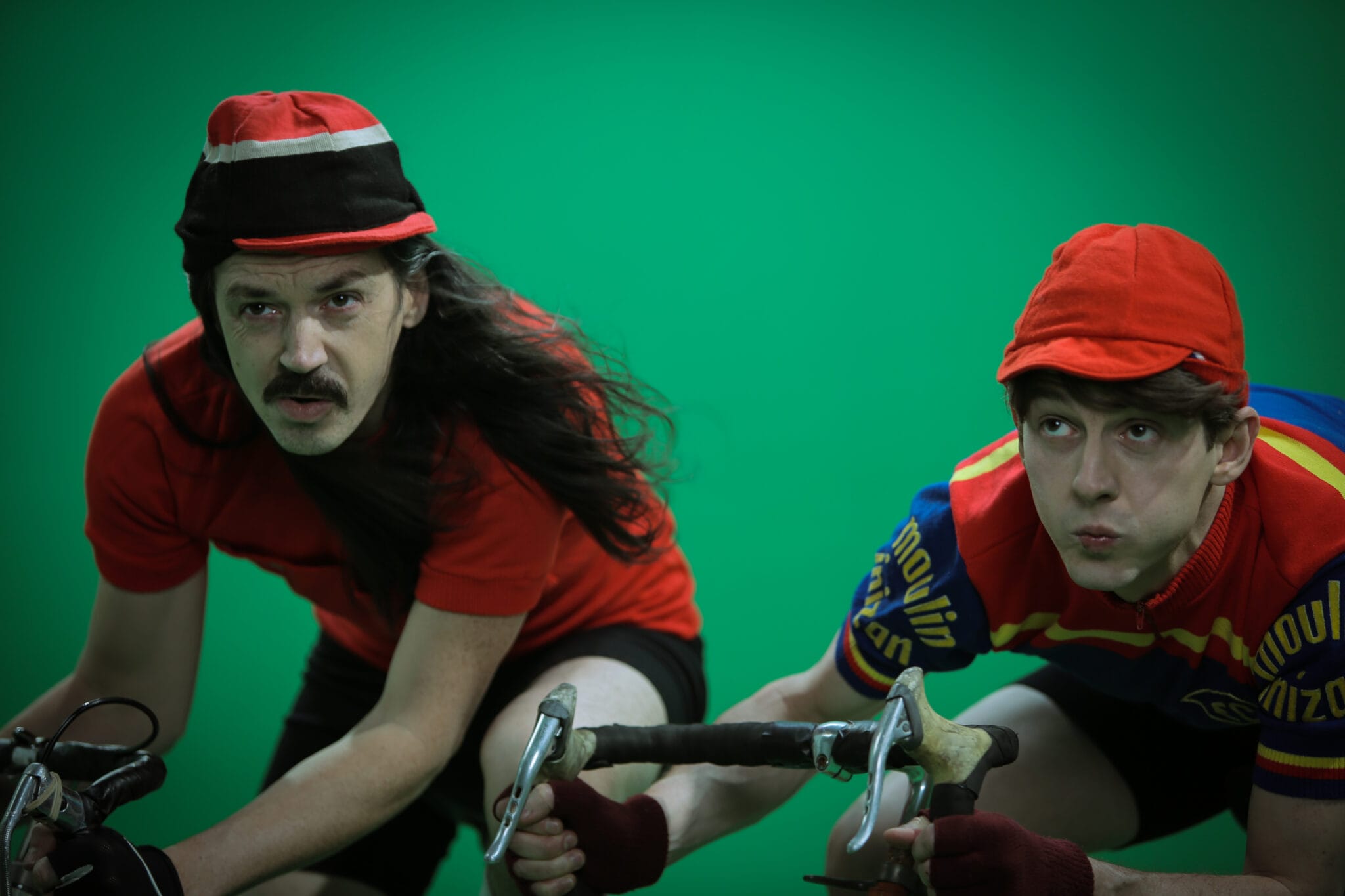 Two cyclists in retro outfits filming on a green screen at the Multivert studio